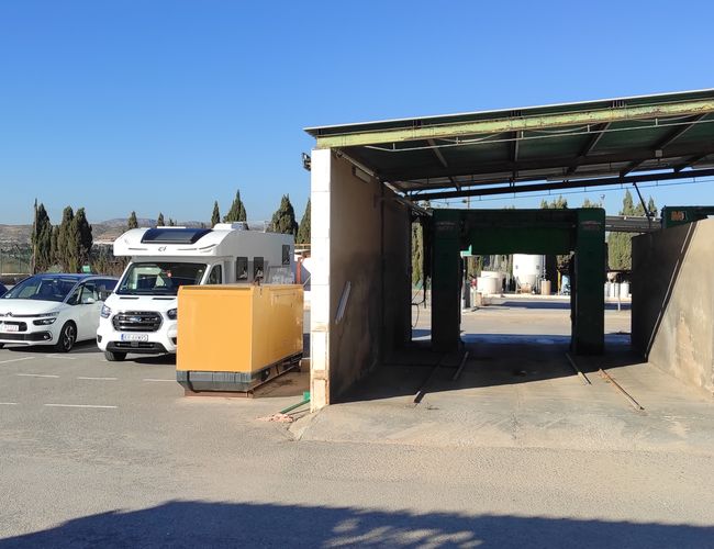 Parking Odkryj-Auto – Parking z kilkoma samochodami i kamperem. Obok znajduje się opuszczona myjnia samochodowa.