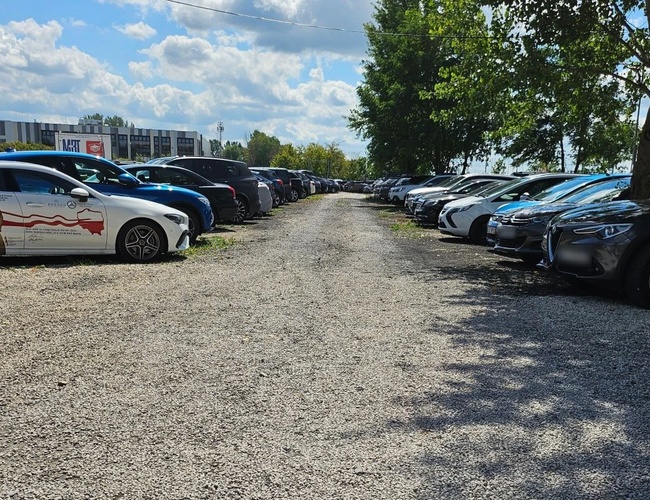 VIP Parkovisko - pri trase S2. Parkovisko s štrkovým povrchom s autami. Obklopené stromami, dobre osvetlené.