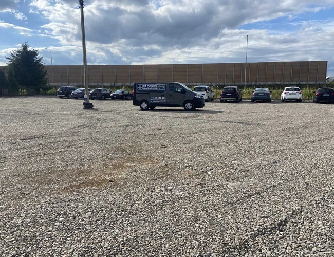 Parkovisko Na Odlete – Veľké štrkové parkovisko. Automobily sú zoradené v radoch. Pozemok je obklopený akustickou obrazovkou.