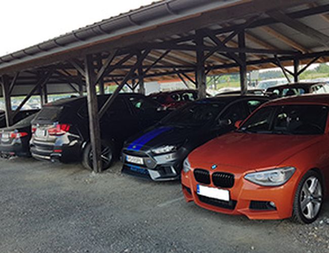 Parking MTM – Zadaszony obszar z zaparkowanymi samochodami. Różne modele stoją obok siebie. Wiata chroni pojazdy przed warunkami pogodowymi.