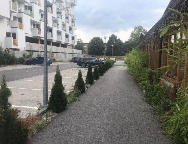 Parkplatz Flughafen Parkplatz - Parkplatz mit Betonboden und einigen Autos. Daneben befindet sich ein Gehweg mit Pflanzen.