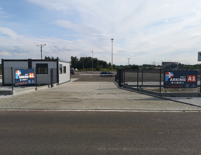 Parkovisko A1 Rondo - Objazd je oplotený a pokrytý kockou. Je viditeľná budova s označením.