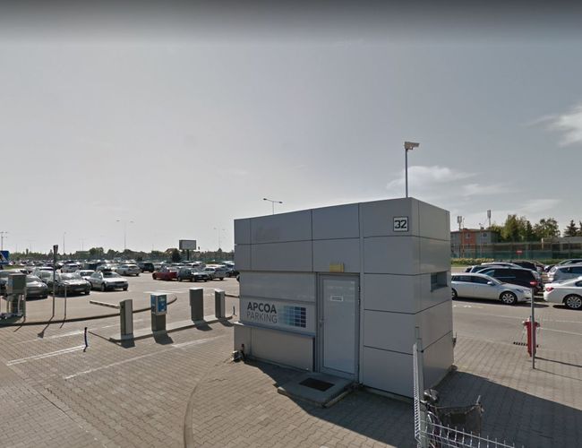 Oficjalny parking P2 - Duży, ogrodzony parking z budką strażnika. Samochody stoją w rzędach. Prowadzą do niego wyraźne oznaczenia.