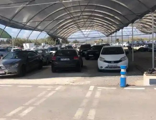 Parking Drimo Park Valet - Samochody stoją pod szeroką wiatą. Teren jest zadaszony i przestronny. Widać wiele zaparkowanych aut.