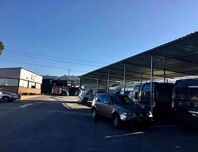 PARK SANSECAR VALET - El estacionamiento es cubierto y espacioso. Varios coches aparcados están en fila. Al fondo se ve un edificio.