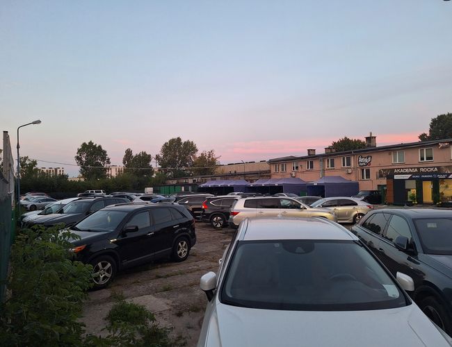 Widok samochodów zaparkowanych na terenie parkingu na tle zachodu słońca.