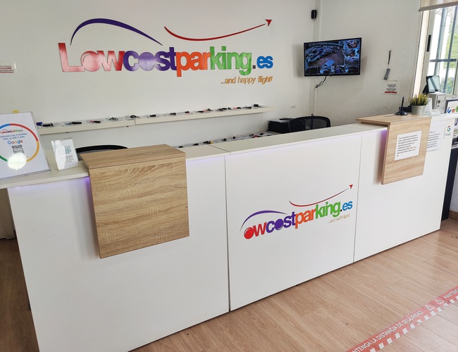 Lavkost parkering Valencia – Resepsjonsdisk med bedriftslogo. På veggen henger en skjerm med kambildet.