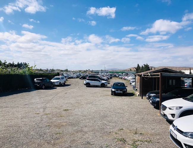 Sunline Parking Outdoor Valet - Na otvorenom terene stoje autá. Parkovisko je štrkové a neobrnené. Vedľa stojí malý drevený objekt.