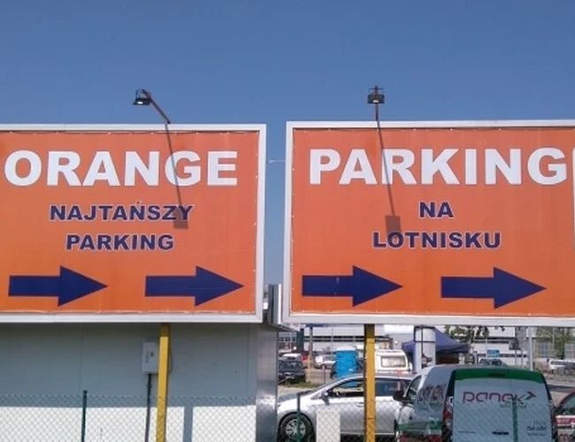 Orange Parking P3 - Dwa pomarańczowe billboardy wskazują kierunek. Znaki informują o parkingu 24 godziny na dobę. W tle widać samochody.