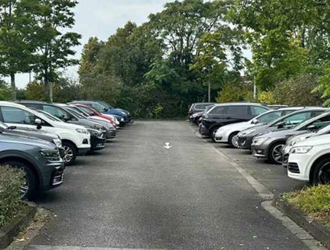 ParKing’s Düsseldorf Outdoor Valet – Samochody stoją w równych rzędach. Teren jest otwarty, otoczony zielenią i drzewami.