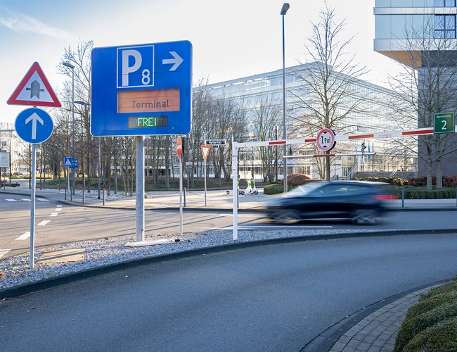 Drogowskaz prowadzący do parkingu P8 z czytelnym oznakowaniem oraz drogą dojazdową w pobliżu terminalu.