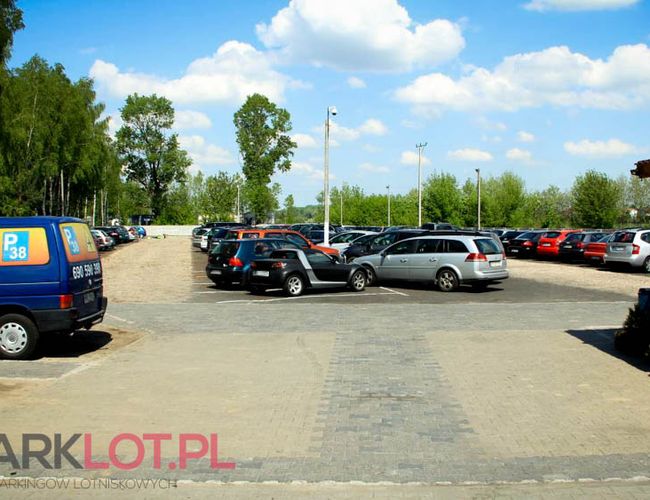 Aparcamiento P38 - El terreno está abierto y espacioso. Los coches están estacionados en filas iguales. En el fondo se pueden ver árboles.