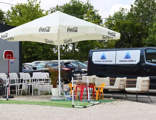 Najlepšia parkovacia séria A - Zóna odpočinku s slnečníkom a stoličkami. Vedľa stojí dodávka s logom parkoviska.