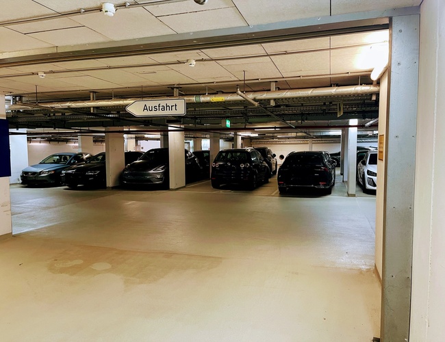 Royal Valet Parking - Niekoľko áut zaparkovaných v podzemnej garáži. Svetlo osvetľuje dobre viditeľnosť. Tabla znamená odchod.