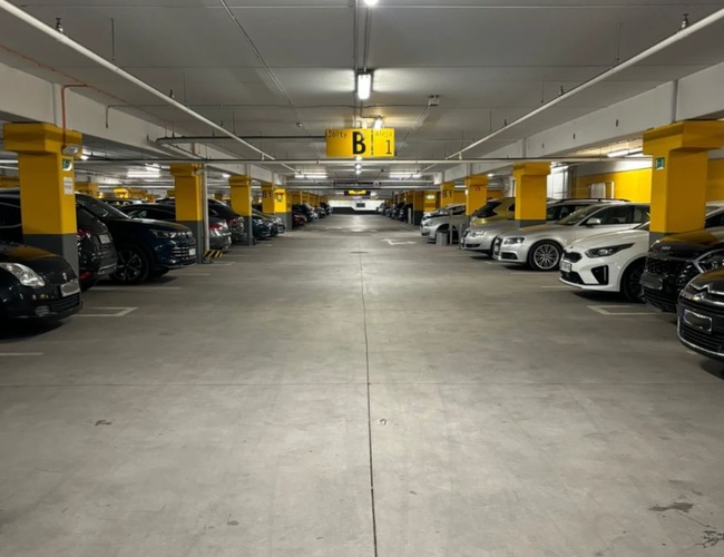 Parkovisko MarcelinPark – Vo vnútri je veľa parkovacích miest. Automobily stoja v rovnakých radoch. Areál je jasne osvetlený.