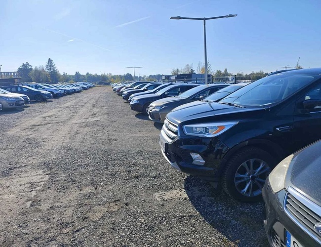 Parking na 5 - Teren jest pełen aut, po obu stronach alejki. Parking jest odkryty i nieogrodzony. Lampy uliczne zapewniają oświetlenie.