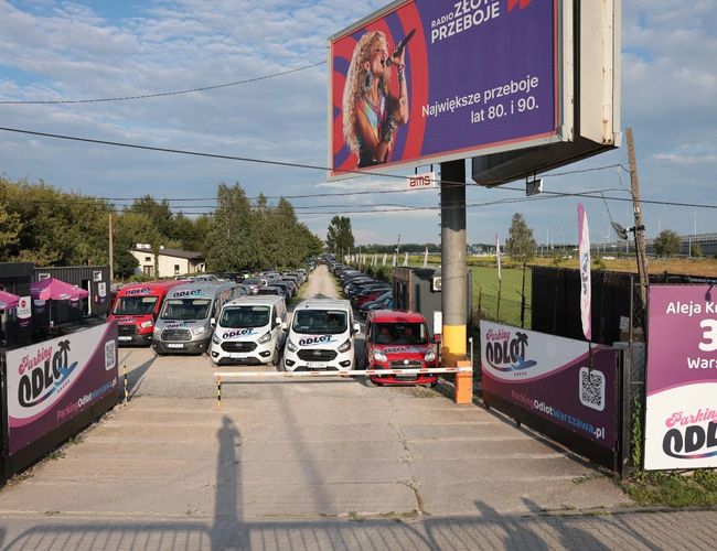 Parkolás Indulás – recepció kanapéval és italautomatával. A pulton szórólapok vannak. A háttérben látható egy megfigyelő monitor.