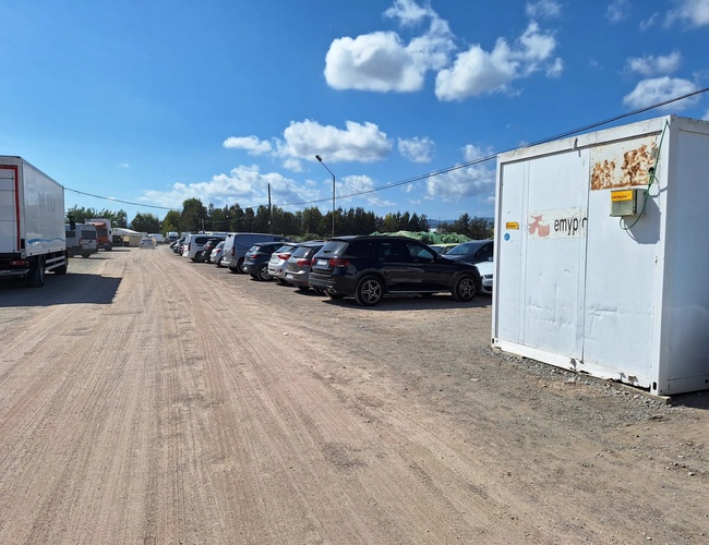 Parkovanie Low Valet - Miesto s zaparkovanými autami na pravej strane. Na ľavej strane stojí nákladné auto. Nebo je modré s niekoľkými oblakmi.