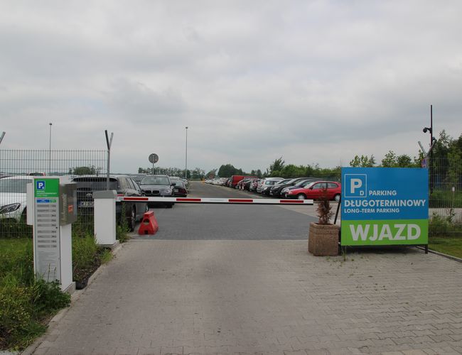 Oficjalny Parking Lotnisko Wrocław Strachowice – parking jest ogrodzony. Na wjeździe znajduje się szlaban. Obok stoi znak wjazdu.