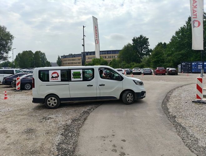 WAW Parking – Na zdjęciu bus przed hotelem. Budynek ma wiele okien. Obok znajduje się inny bus.