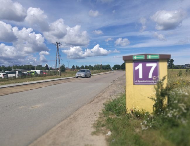 Parking P8 – Teren jest ogrodzony metalową siatką. Widać kilka samochodów zaparkowanych obok siebie.