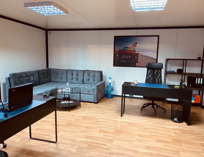 Kraków KING Parking – Kancelária so sivým rohom a pultom. Na stene visí obraz auta na pláži.