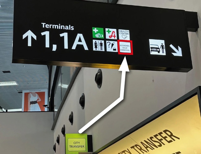 Aparcamiento Parktiger Transfer - Las señales indican la dirección hacia las terminales. Las flechas y el texto señalan el camino hacia los transferencias urbanas.