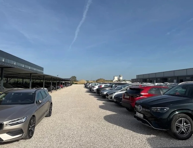 Samochody zaparkowane na dużym, utwardzonym placu parkingowym w ciągu dnia