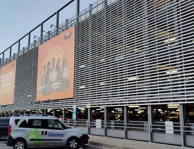 Widok na wielopoziomowy parking lotniskowy z nowoczesną elewacją z metalowych paneli, zapewniający dużą liczbę miejsc postojowych w pobliżu terminala.