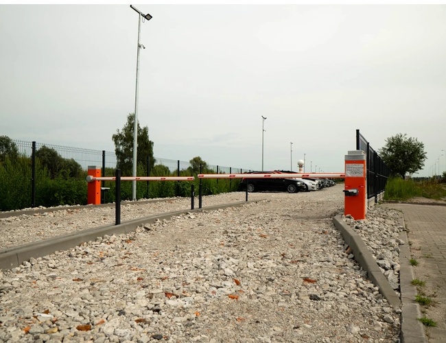 Simple Park – Oplotené parkovisko s rampou pri vstupe. Pozdĺž cesty stoja zaparkované automobily.