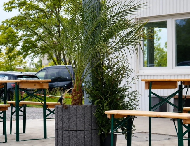 Aparcamiento myParkplace - Se pueden ver varios coches aparcados junto al edificio. En el edificio se han instalado cámaras y hay un cartel publicitario de café visible.
