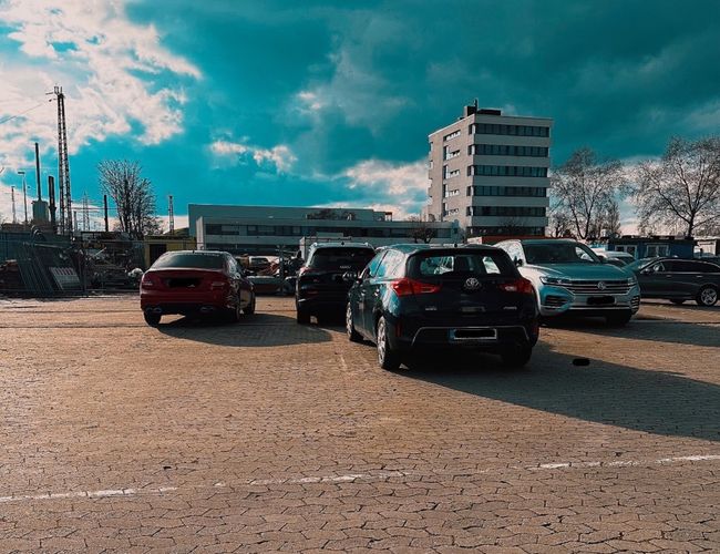 Parking Safetyparking24 VALET - Na parkingu stoi kilka samochodów. W tle widać wysokie budynki.