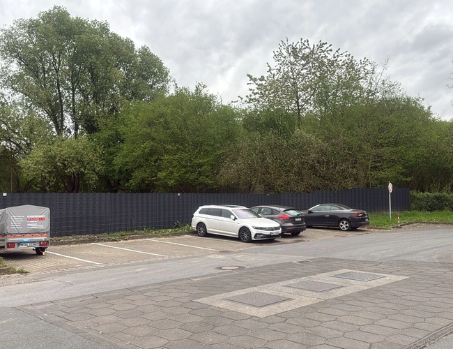 Parking Trust Park Fly - Na parkingu stoją trzy samochody. Teren jest ogrodzony i otoczony drzewami. Pogoda jest pochmurna.