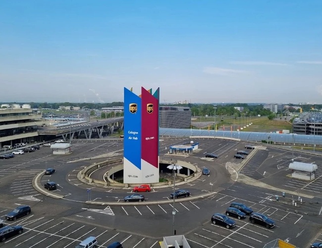 Panorama oficjalnego parkingu P1 na lotnisku Cologne Bonn z charakterystycznym pylonem informacyjnym oraz rozbudowanym układem dróg prowadzących do terminali.
