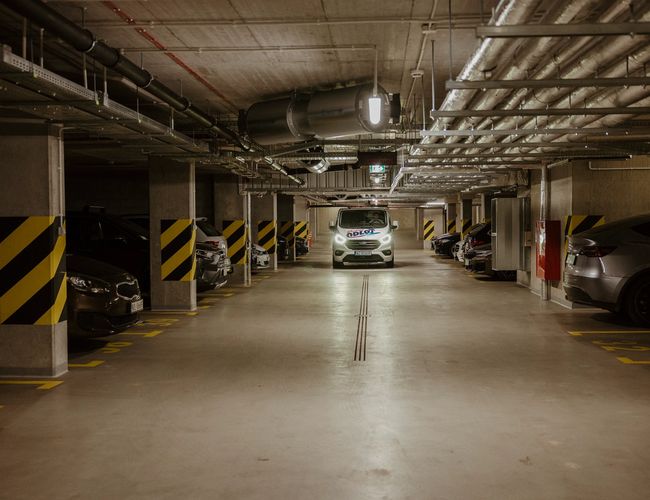 Odlot Garage - Podziemny parking oświetlony neonowym światłem. Samochody stoją w wyznaczonych miejscach.
