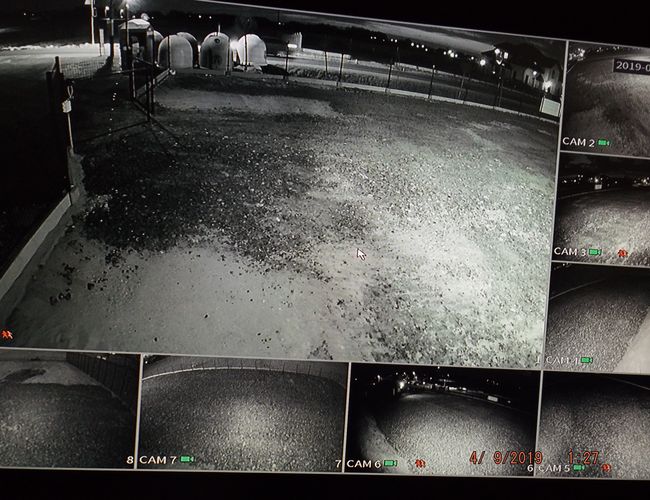 VIP Parking - ogrodzony plac monitorowany nocą. W tle widać oświetlenie. Na ekranie pokazano różne ujęcia z kamer.