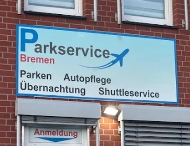 Parking Parkservice Bremen. Szyld z napisem informującym o usługach parkingowych, myciu samochodów oraz shuttle service.