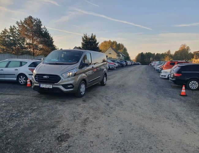 Parking Wings - En el área de grava están estacionados los autos. Se pueden ver vehículos de entrega y coches particulares. Al lado, hay conos naranjas colocados.