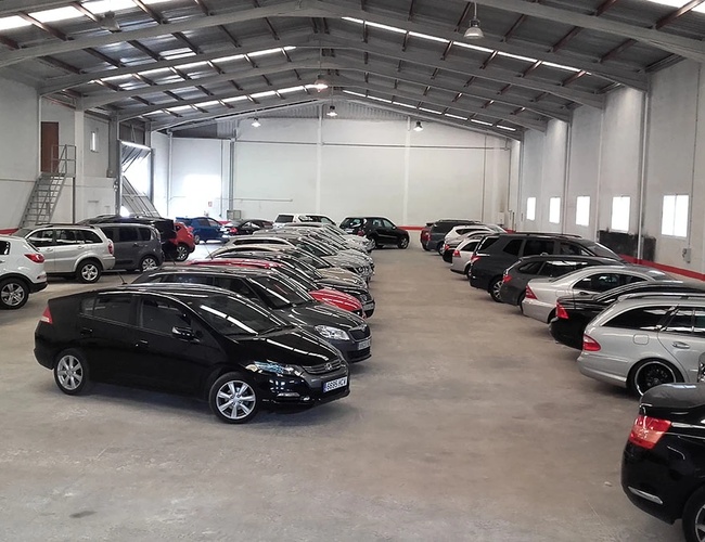 Lavkostparkering Valencia – parkering inne i en stor hall. Biler står i rader. Hallen er lys med tak av metall.