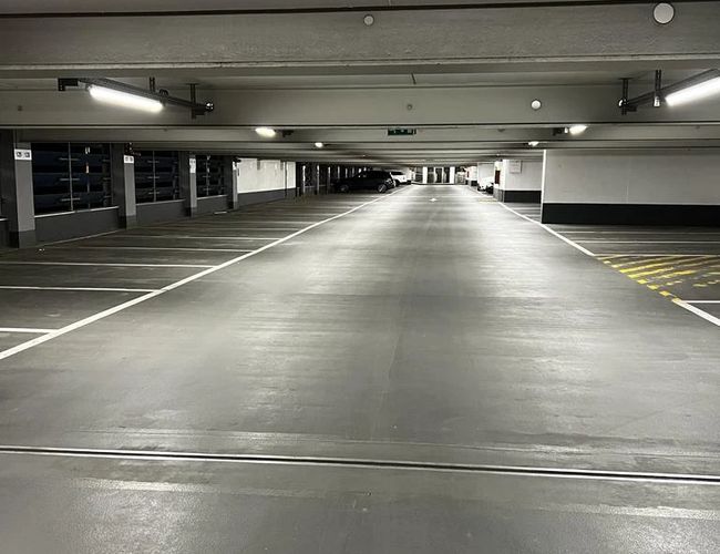 Parking Park2Travel Valet Garage - Wnętrze zadaszonego parkingu. Jasne oświetlenie oraz wyraźnie oznaczone miejsca postojowe.