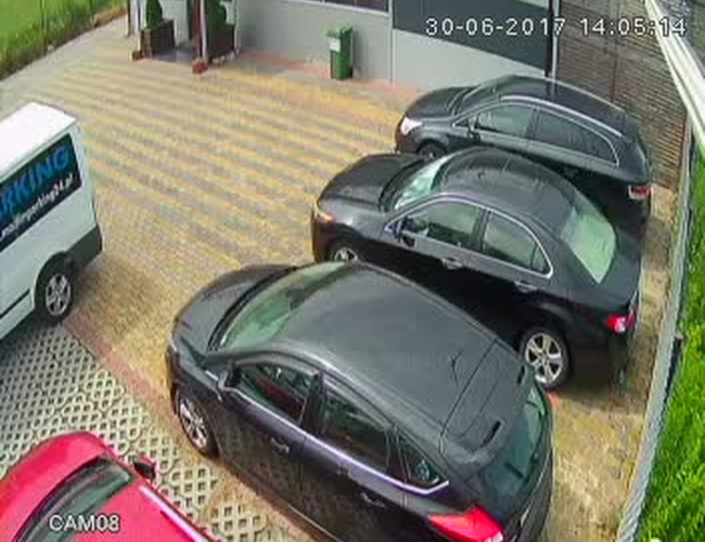 PARKING P24 PREMIUM – Widoczne zaparkowane samochody na brukowanym placu. Teren jest ogrodzony i dobrze utrzymany.