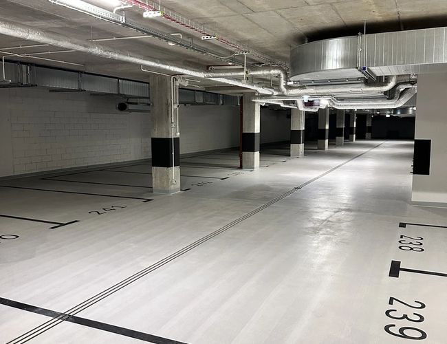 Supreme Parking Garage - Podziemny, nowoczesny parking z oznaczonymi miejscami. Światło i wentylacja są widoczne na suficie. Przestrzeń jest jasna i czysta.