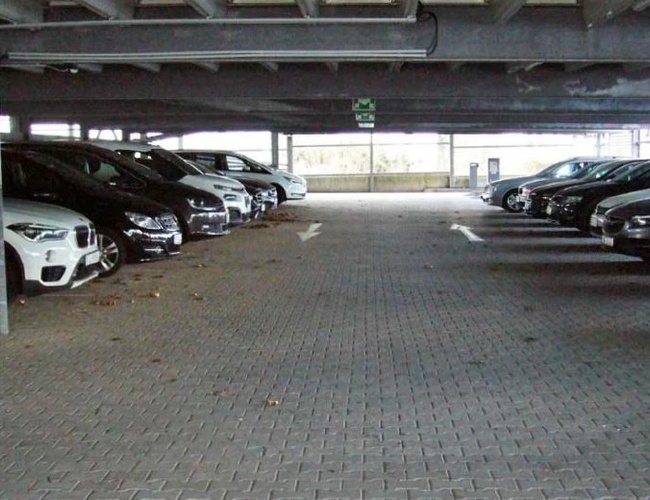 ParKing’s Düsseldorf Covered Valet – Zadaszony parking z samochodami zaparkowanymi po obu stronach. Betonowa nawierzchnia jest czysta i przestronna.